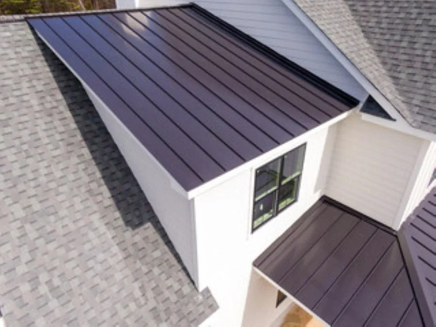 Standing-seam metal roof sections beside gray asphalt shingles