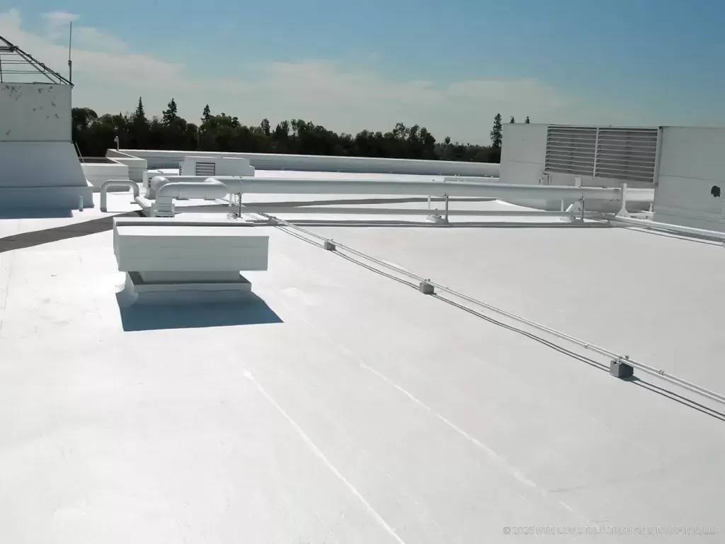 White low-slope commercial roof with rooftop equipment and flashed penetrations