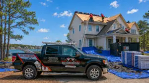 RGR Construction and Roofing truck at a Wilmington NC roof replacement project with CertainTeed Landmark Pro shingles, roofers in red shirts, protective tarps, and roofing materials on site.