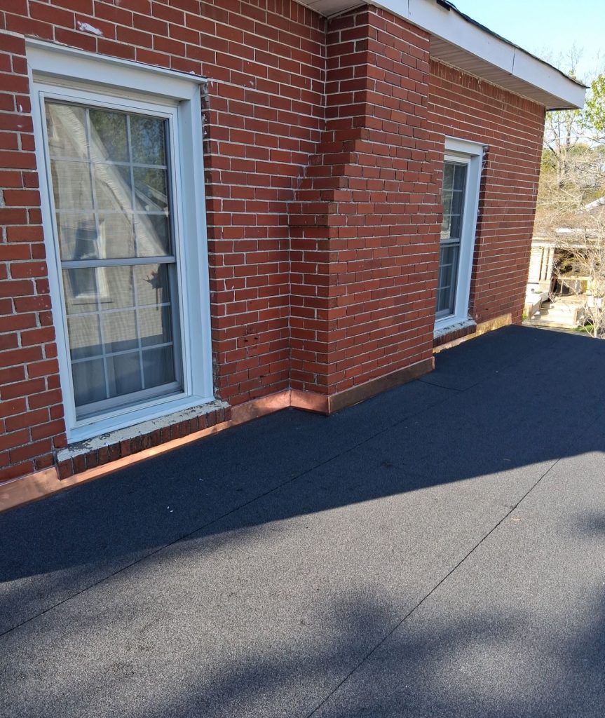 Completed granular flat roof with copper flashing beneath windows on a Wilmington brick home