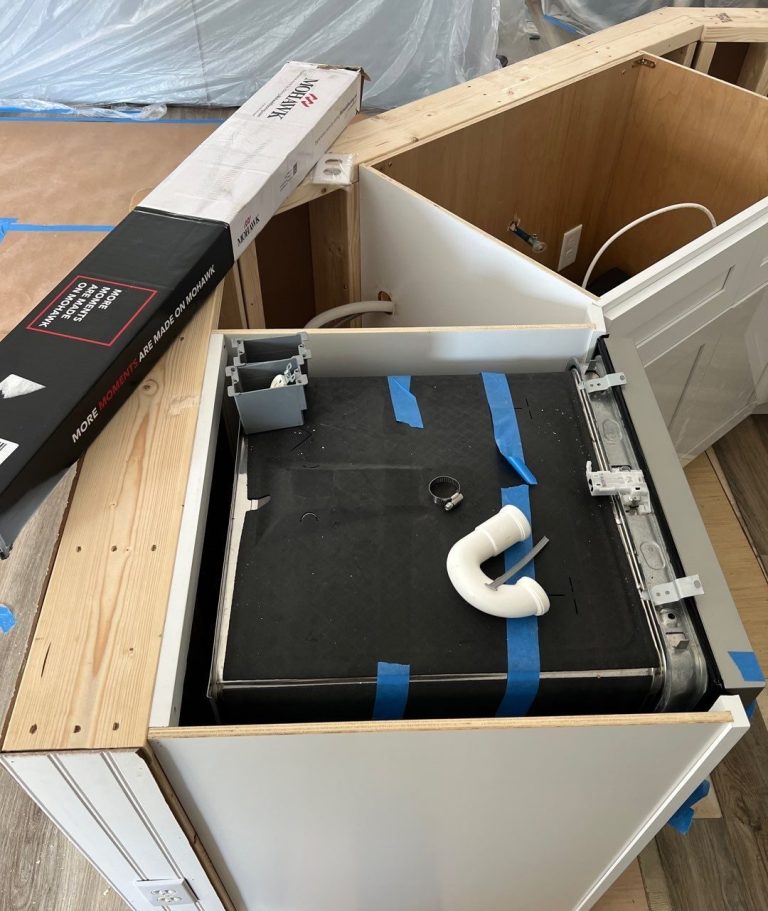 Open sink cabinet during water-damage repairs in Carolina Beach