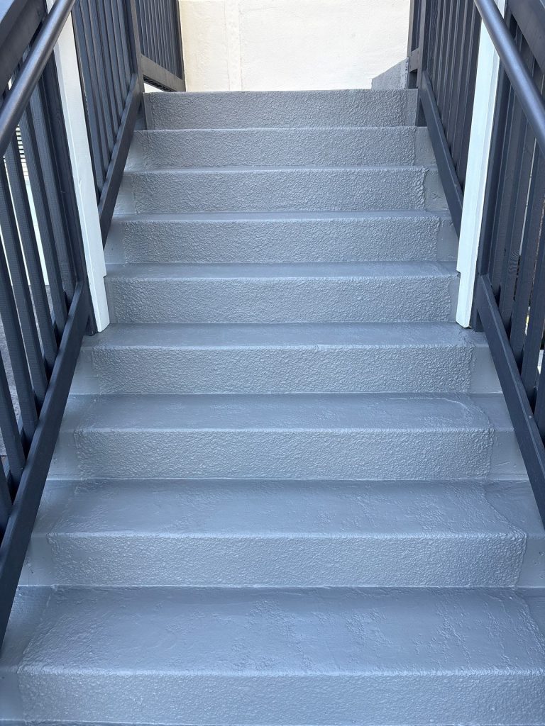 Gray-coated concrete stair treads and risers between dark railings in Wrightsville Beach