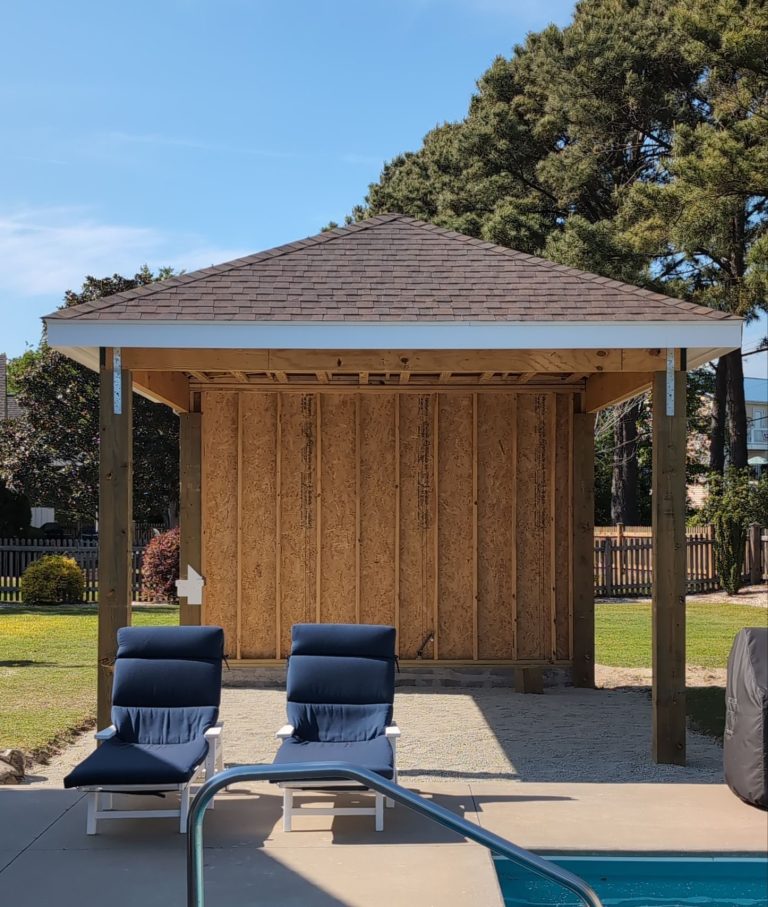 Gazebo shingle roof above wood posts and exposed wall sheathing beside a swimming pool in Hampstead