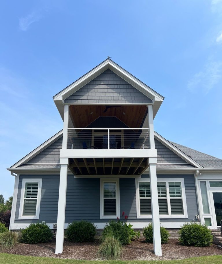 Completed elevated covered porch with gable roof and cable railing at a Leland home