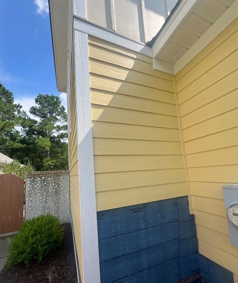 Blue wall backing exposed below yellow siding during exterior wall repair in Waterford, Leland