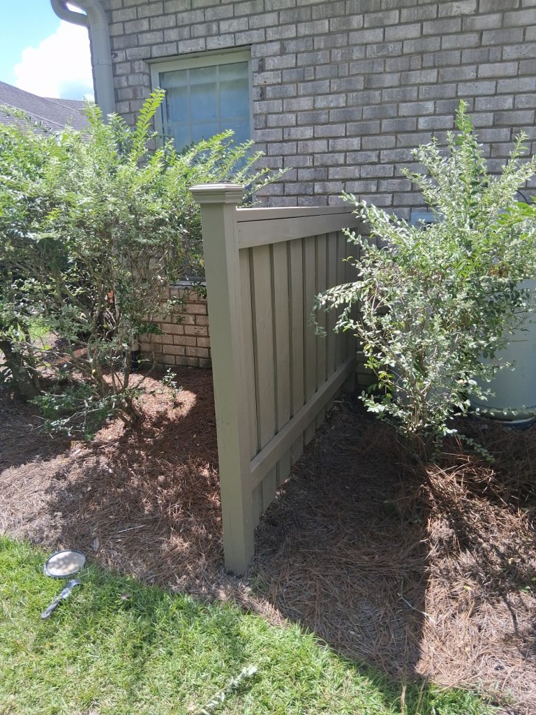 Stained wood fence and capped post beside a brick home in Leland