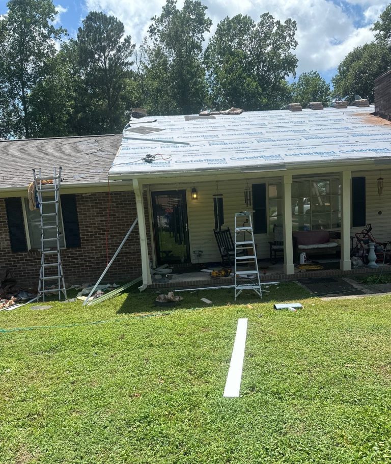 Underlayment across part of a residential roof with ladders and roofing materials in place