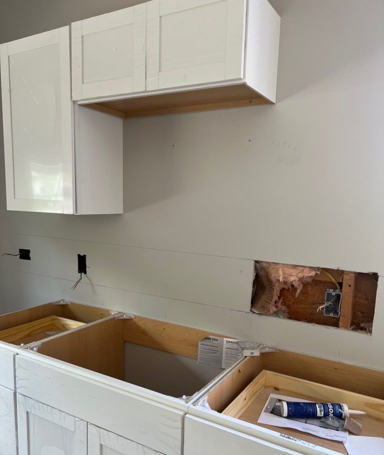 Open cabinet boxes and wall work during the Belville interior remodel