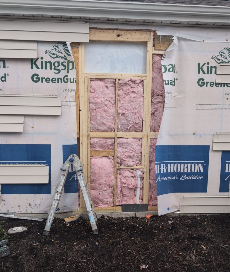 Exposed wall framing and insulation below the bathroom window opening