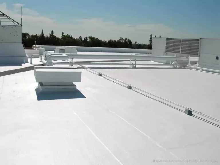 White low-slope commercial roof with rooftop equipment and flashed penetrations