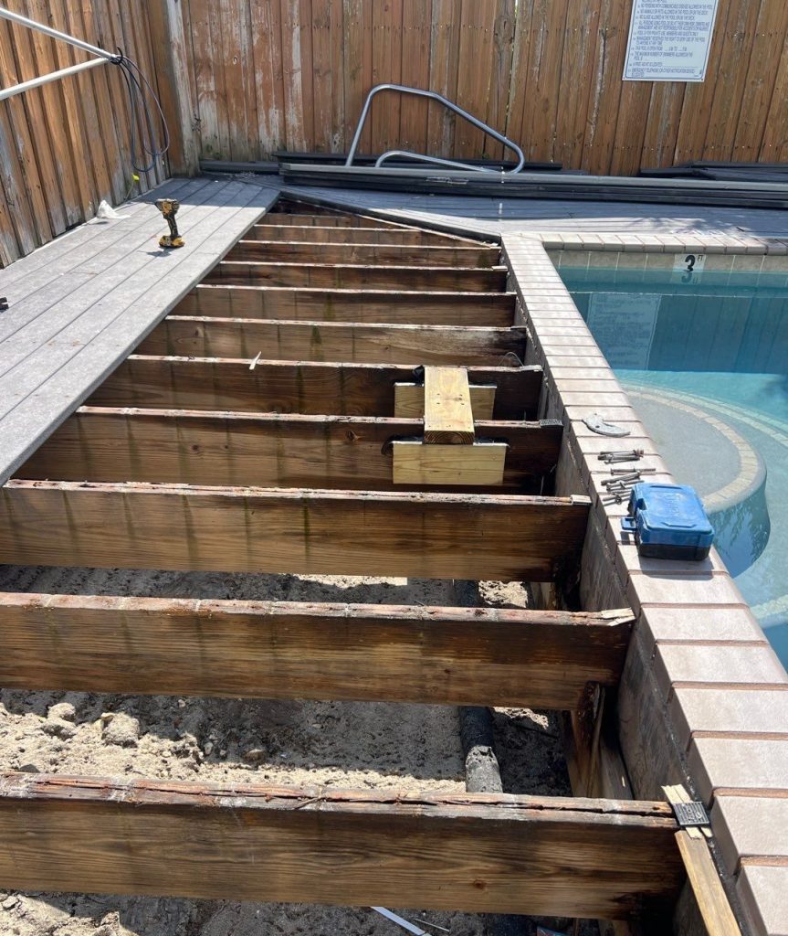 Exposed wood deck joists beside a swimming pool during structural repair in Carolina Beach
